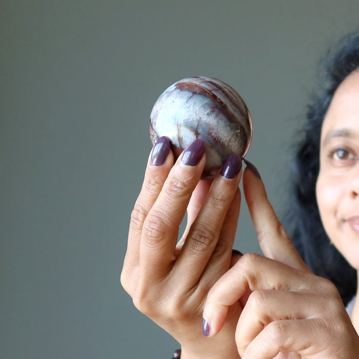 fingers holding Blue Red Chalcedony Sphere