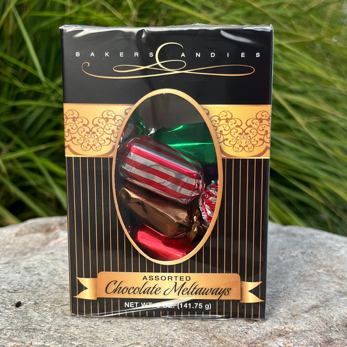 Bakers Candies 5oz Chocolate Meltaways Window Box Sitting outside on a rock with a grass background.
