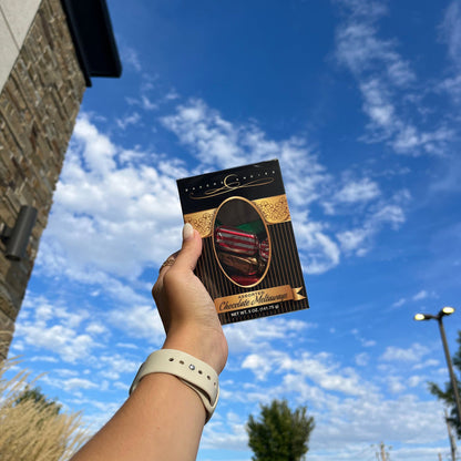 Bakers Candies 5oz Chocolate Meltaways Window Box Being held by a person in front of a sky background.