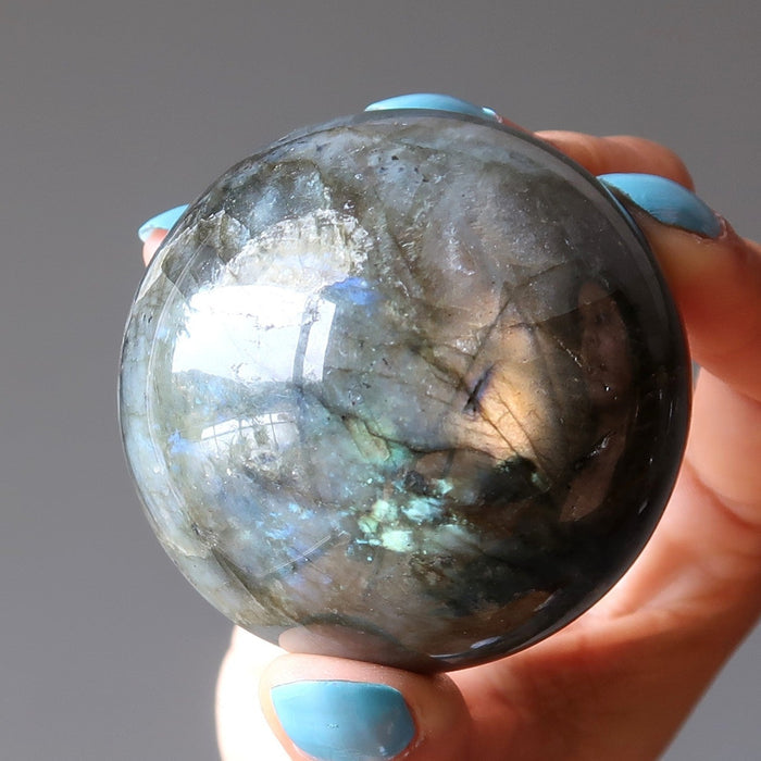 hand holding up a rainbow labradorite sphere