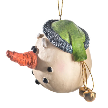 A snowman ornament with a textured cream-colored body, a green and gray knit hat, an orange carrot nose, and small gold bells hanging from a gold hanging string, shown on a plain white background.